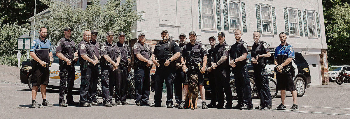 Village of Delhi police officers and dog posing in front of village hall